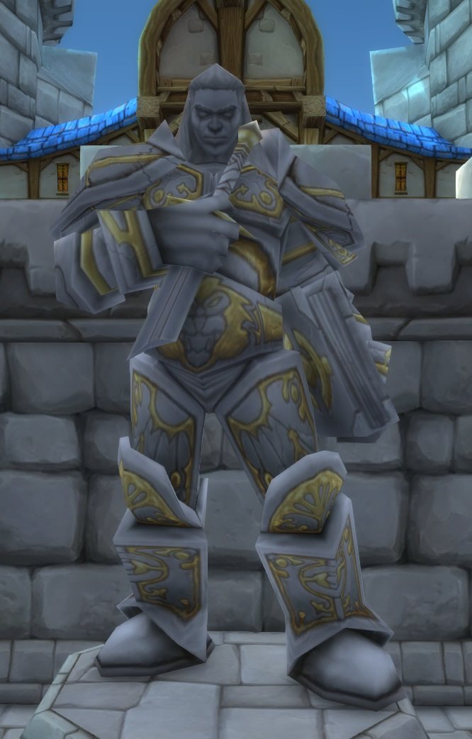 The in-game statue of Turalyon: grey plate with gold filigree, a stern face, standing on a plinth against a Stormwind wall.